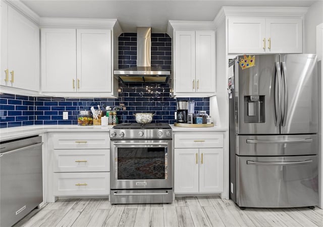 kitchen with wall chimney range hood, white cabinetry, stainless steel appliances, and light countertops