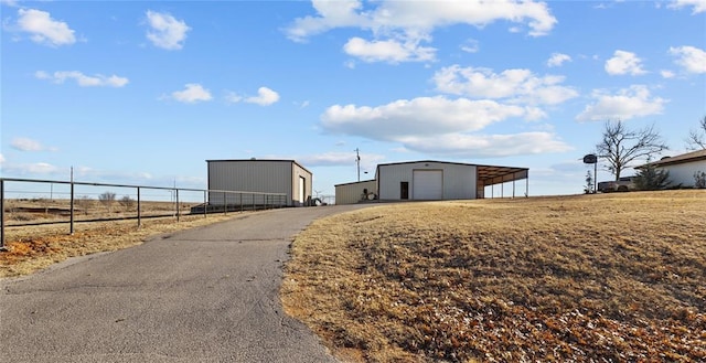 view of road featuring a rural view, aphalt driveway, and an outbuilding