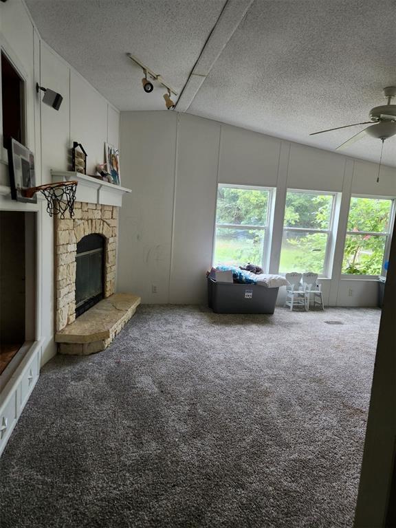 unfurnished living room featuring a fireplace, carpet flooring, a textured ceiling, and rail lighting