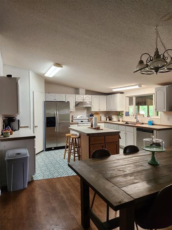 kitchen featuring sink, white cabinetry, dark hardwood / wood-style flooring, a kitchen island, and stainless steel appliances