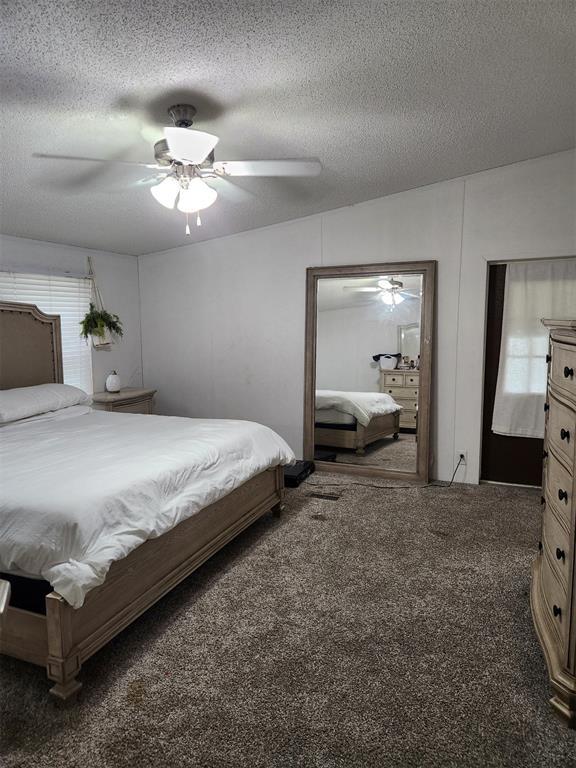 carpeted bedroom with ceiling fan and a textured ceiling