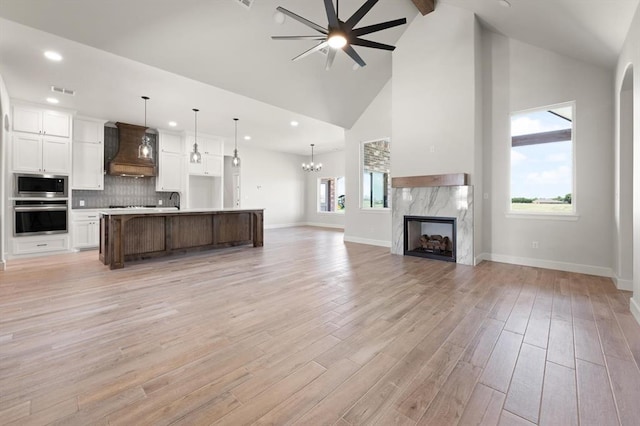 4341 Courtlyn Ave, Tuttle, OK 73089 - kitchen with stainless steel appliances, premium range hood, open floor plan, white cabinets, and light countertops