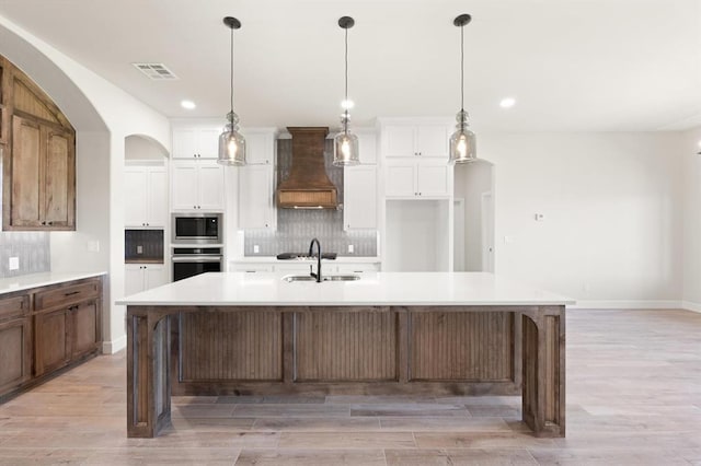 4341 Courtlyn Ave, Tuttle, OK 73089 - kitchen featuring stainless steel appliances, custom range hood, a sink, backsplash, and light wood-style floors