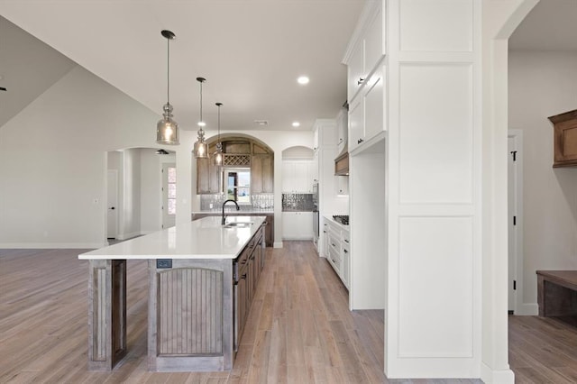 4341 Courtlyn Ave, Tuttle, OK 73089 - kitchen with arched walkways, a sink, light wood finished floors, tasteful backsplash, and a large island