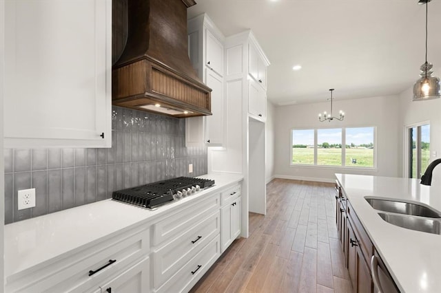 4341 Courtlyn Ave, Tuttle, OK 73089 - kitchen featuring a sink, custom exhaust hood, stainless steel gas cooktop, light countertops, and light wood finished floors