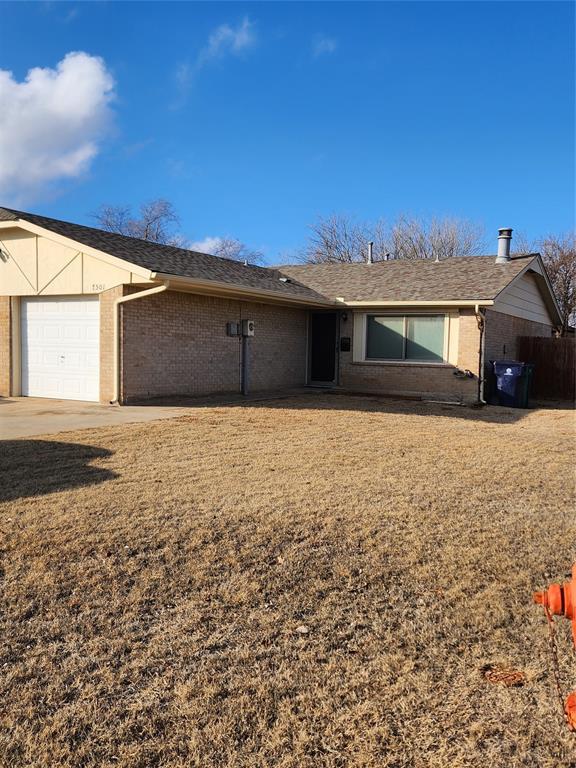 ranch-style home with a garage and a front lawn