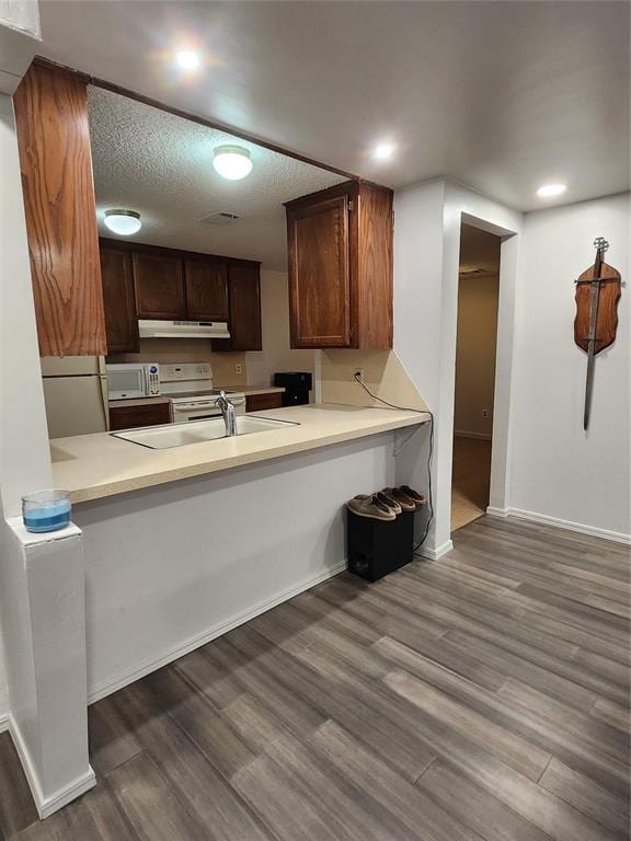 kitchen with dark brown cabinets, dark hardwood / wood-style floors, and kitchen peninsula