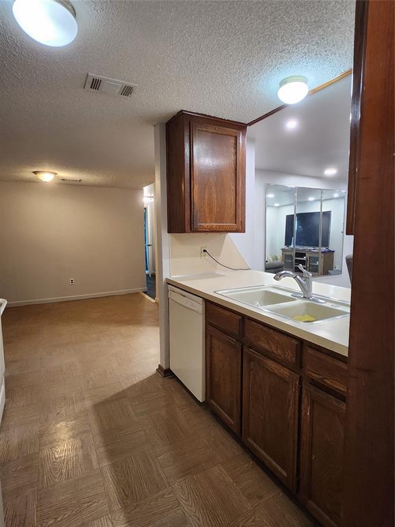 kitchen featuring dishwasher, sink, and a textured ceiling