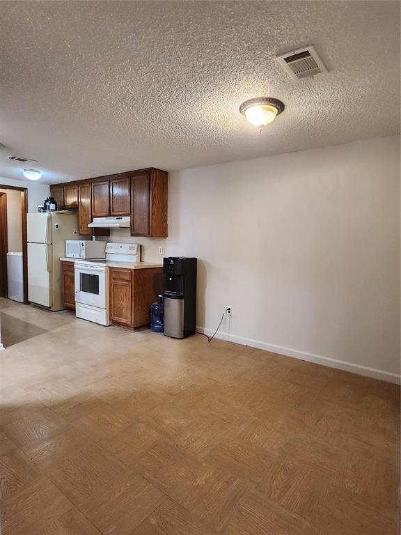 kitchen featuring a textured ceiling and white appliances