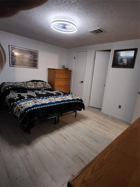 bedroom with light hardwood / wood-style floors and a textured ceiling