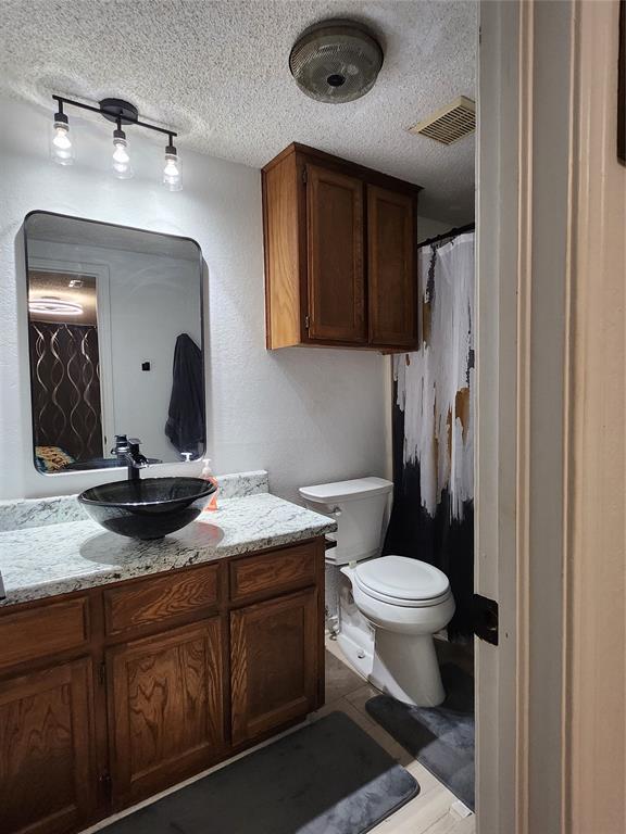 bathroom featuring vanity, toilet, and a textured ceiling