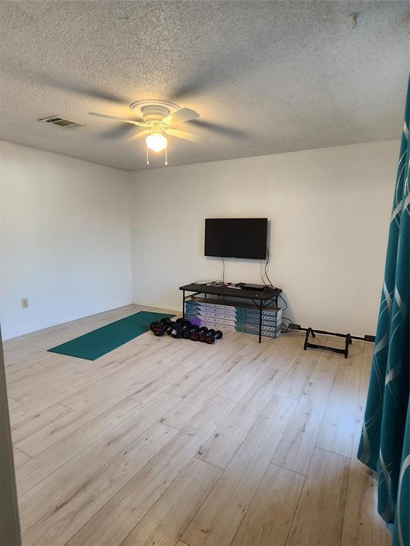 interior space featuring ceiling fan, light hardwood / wood-style flooring, and a textured ceiling