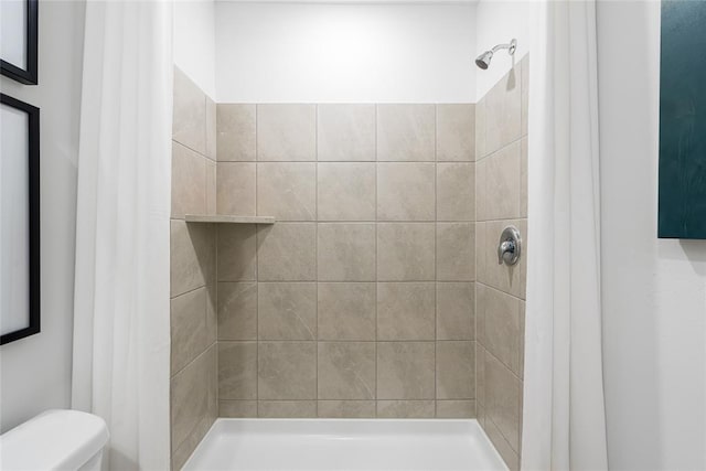 bathroom featuring a tile shower and toilet