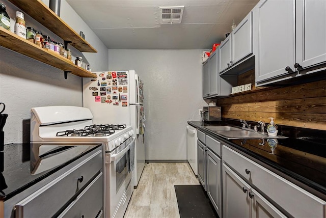 kitchen with gray cabinetry, sink, white appliances, and light hardwood / wood-style flooring