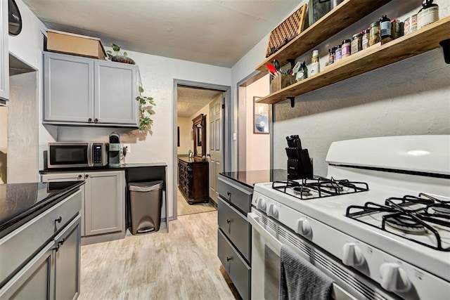 kitchen featuring white range with gas cooktop, gray cabinetry, and light hardwood / wood-style floors