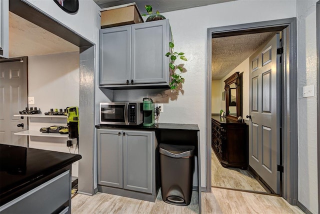 kitchen featuring light hardwood / wood-style floors, a textured ceiling, and gray cabinetry