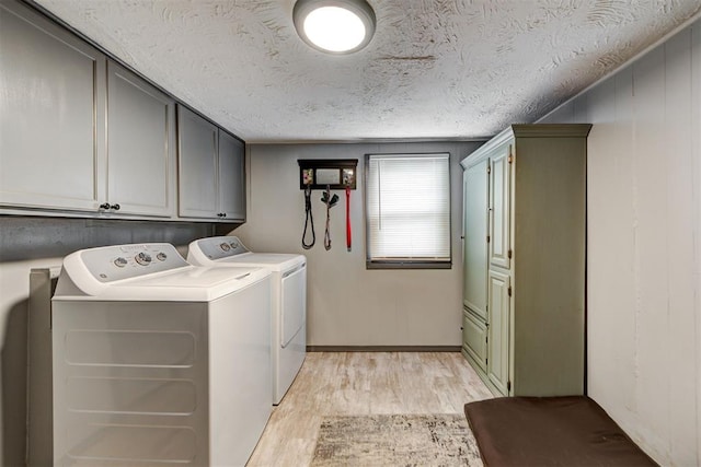 washroom featuring cabinets, washing machine and dryer, a textured ceiling, and light wood-type flooring