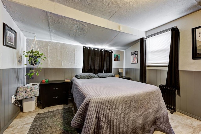 bedroom featuring radiator heating unit, vaulted ceiling, wooden walls, and a textured ceiling