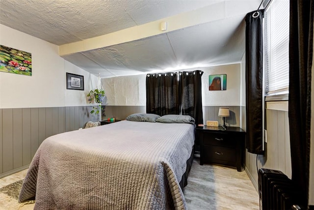 bedroom with vaulted ceiling, a textured ceiling, and light wood-type flooring