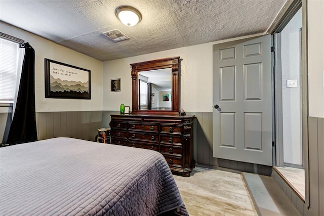 bedroom featuring a textured ceiling and wood walls