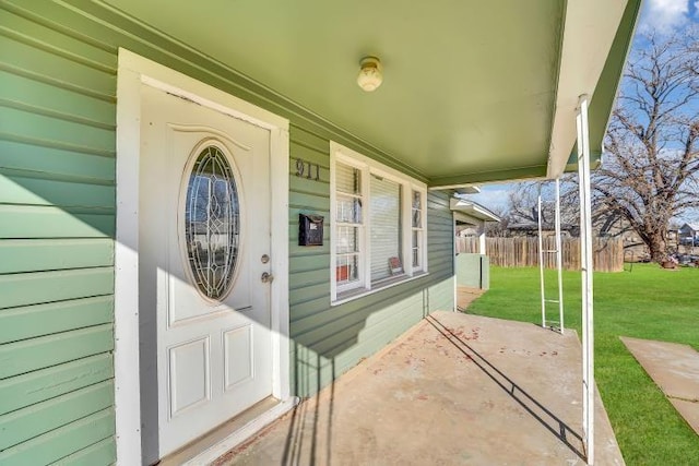 entrance to property featuring a porch and a lawn