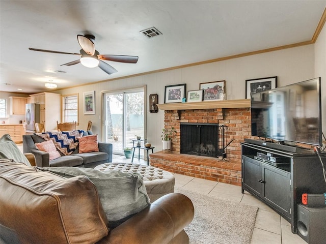 living room featuring light tile patterned flooring, ceiling fan, a fireplace, and crown molding