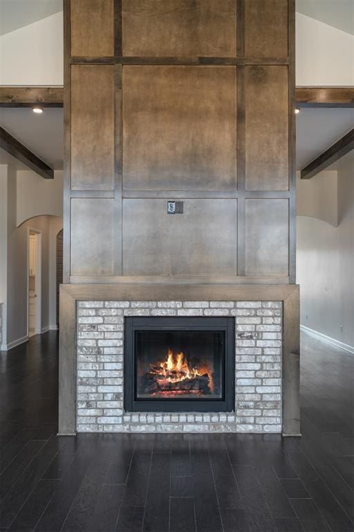 interior details featuring a brick fireplace, baseboards, beam ceiling, and wood finished floors