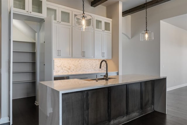 kitchen with glass insert cabinets, light countertops, white cabinetry, pendant lighting, and a sink