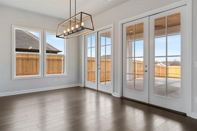 interior space featuring dark wood-style floors, french doors, a chandelier, and baseboards