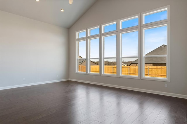 empty room with high vaulted ceiling, baseboards, and dark wood finished floors