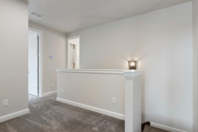 unfurnished room featuring dark colored carpet, visible vents, and baseboards