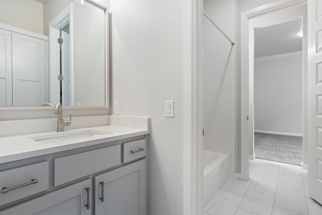 bathroom featuring washtub / shower combination, marble finish floor, vanity, and baseboards