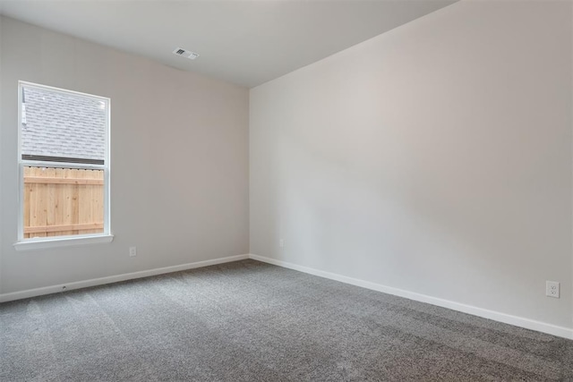 spare room with carpet floors, visible vents, and baseboards