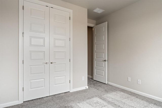 unfurnished bedroom featuring a closet, light carpet, and baseboards