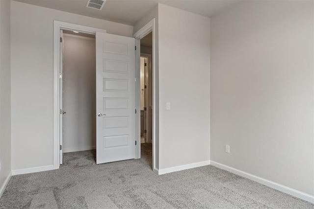 unfurnished bedroom featuring visible vents, light carpet, and baseboards