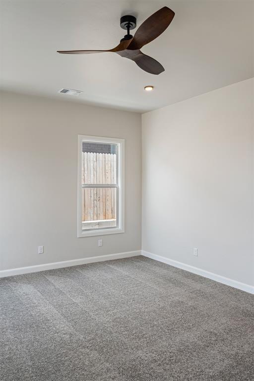 spare room featuring ceiling fan, carpet flooring, visible vents, and baseboards