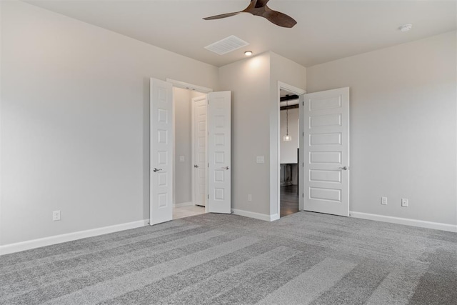 unfurnished bedroom featuring baseboards, ceiling fan, visible vents, and light colored carpet