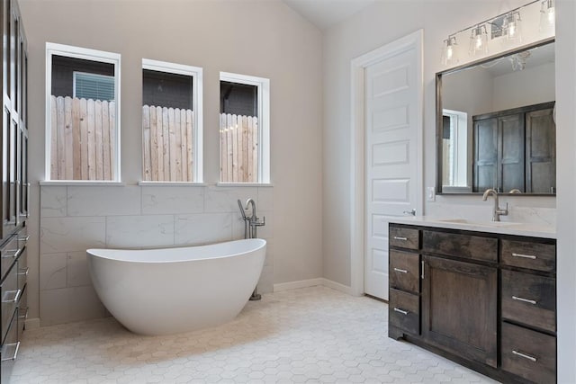 bathroom with a freestanding bath, tile patterned flooring, and vanity