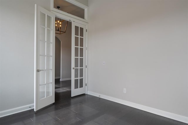 spare room with dark wood-style floors, arched walkways, french doors, and baseboards