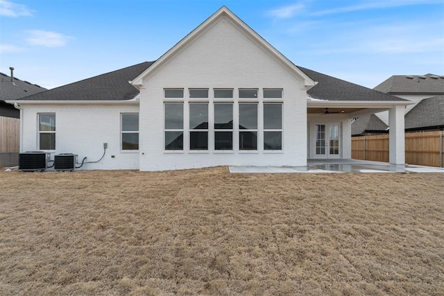 back of house featuring a patio, central air condition unit, brick siding, fence, and a lawn