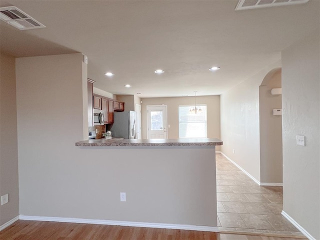 kitchen with stainless steel appliances, hanging light fixtures, and kitchen peninsula