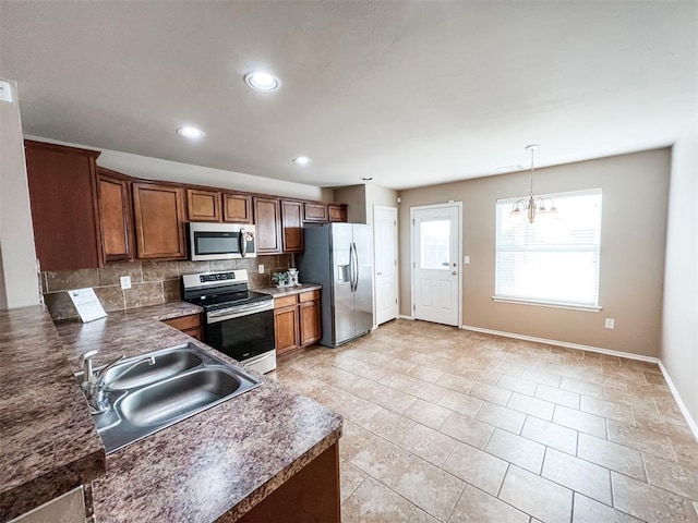 kitchen featuring appliances with stainless steel finishes, decorative light fixtures, sink, decorative backsplash, and a notable chandelier