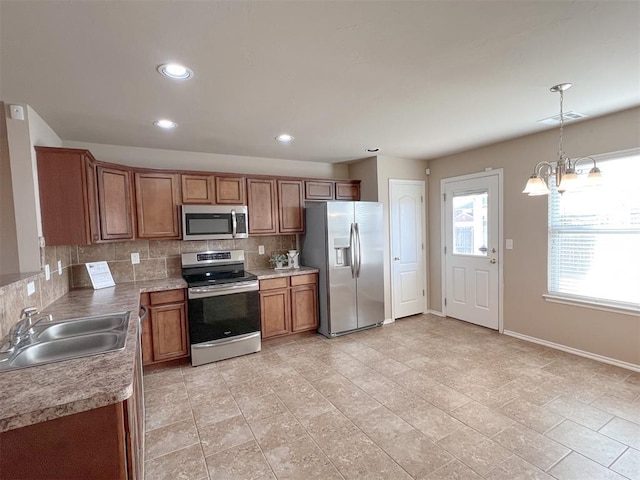 kitchen featuring sink, an inviting chandelier, appliances with stainless steel finishes, pendant lighting, and decorative backsplash