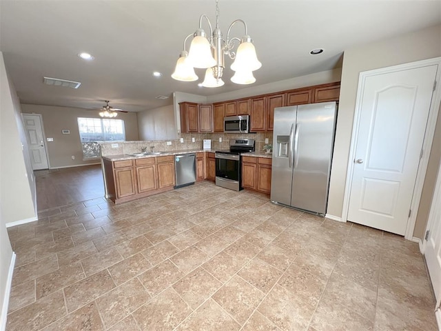 kitchen with sink, appliances with stainless steel finishes, hanging light fixtures, ceiling fan with notable chandelier, and kitchen peninsula