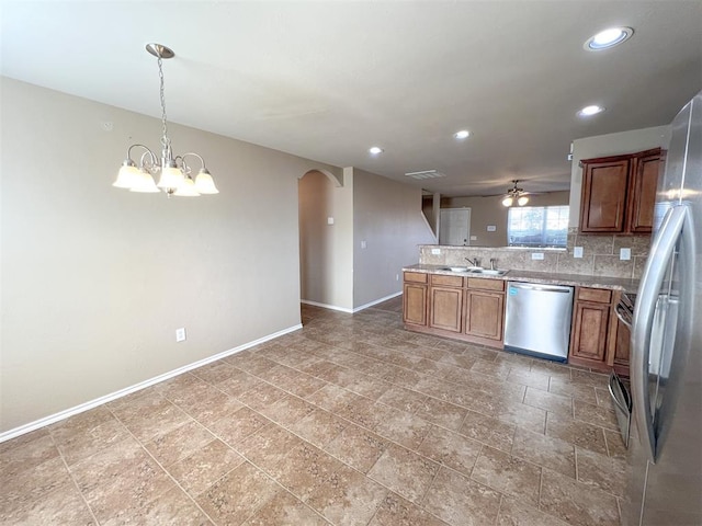 kitchen with pendant lighting, sink, appliances with stainless steel finishes, tasteful backsplash, and ceiling fan with notable chandelier