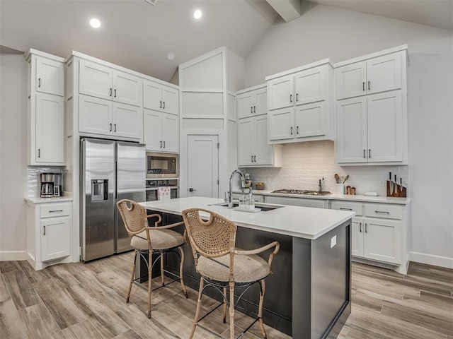 kitchen featuring sink, white cabinetry, a kitchen breakfast bar, stainless steel appliances, and a kitchen island with sink