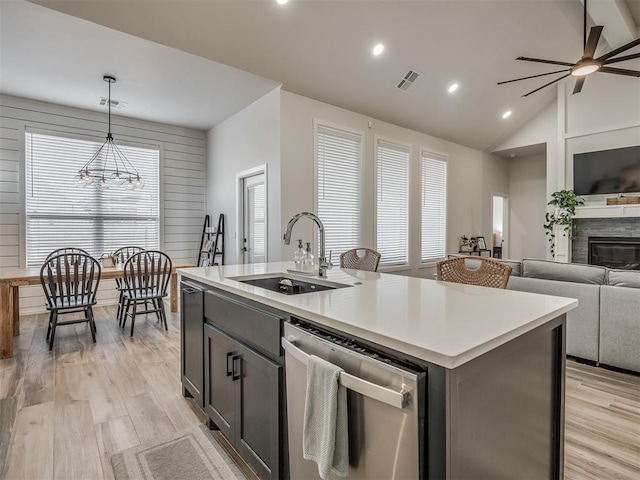 kitchen with sink, decorative light fixtures, a center island with sink, light wood-type flooring, and dishwasher