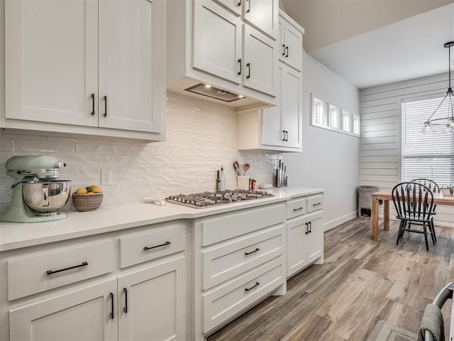 kitchen with white cabinetry, backsplash, decorative light fixtures, and a wealth of natural light