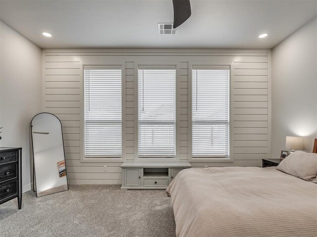 carpeted bedroom featuring wood walls