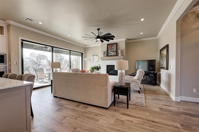 living room featuring crown molding, light wood-type flooring, and ceiling fan